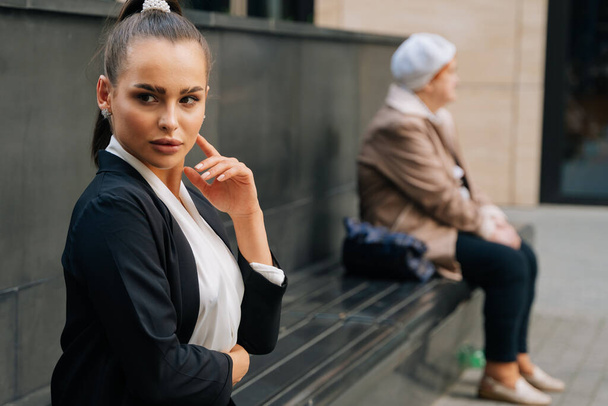 A portrait of a businessman's girlfriend waiting for a customer on a bench during a pandemic. Social distance in a promised place, next to a person - Foto, afbeelding