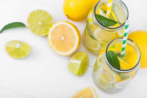 schmackhaftes Limonadengetränk mit Zitrone, Limette und Minze auf holzweißem Tisch. Ansicht von oben - Foto, Bild