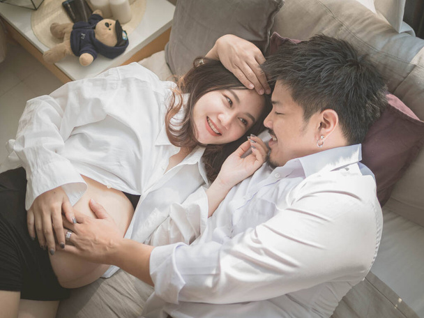 Чоловік азіатського чоловіка дбає про свою вагітну дружину. Красива вагітна жінка та її вродливий чоловік посміхаються, проводячи разом час.. - Фото, зображення