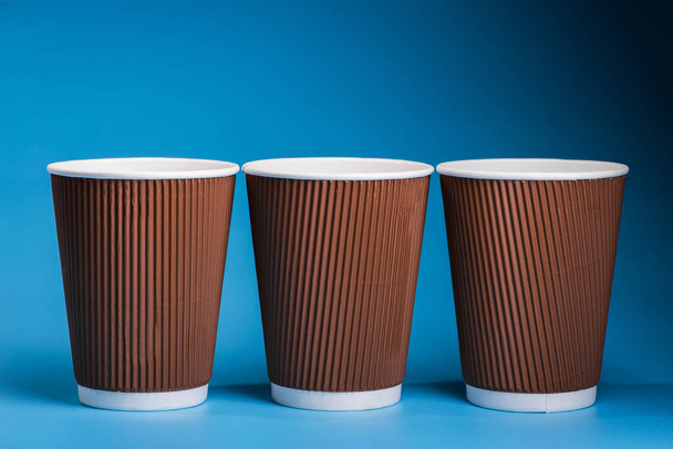 tazas de café de papel sobre fondo azul, envase de bebida para llevar
 - Foto, Imagen