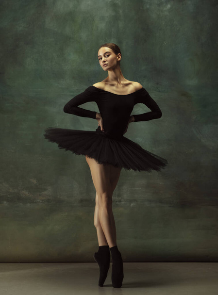 Young graceful tender ballerina on dark studio background - Foto, afbeelding