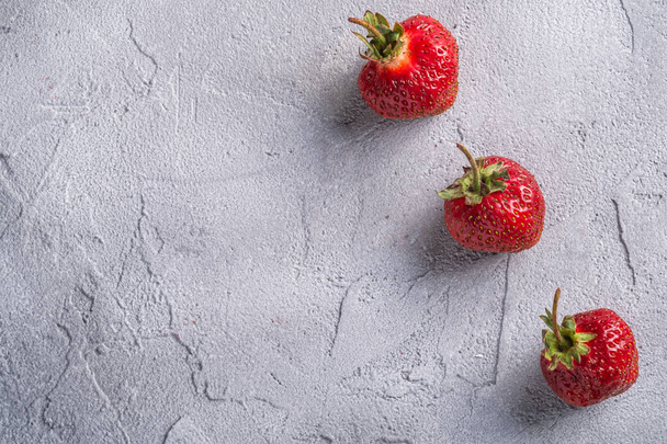 Φρέσκα ώριμα φρούτα φράουλα στη σειρά, καλοκαιρινά μούρα βιταμίνης σε γκρι φόντο πέτρα, top view αντίγραφο χώρο - Φωτογραφία, εικόνα