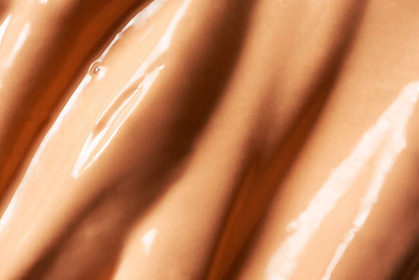Macro BB cream or CC cream luxury smear texture background with selective focus. Beige liquid shiny creamy foundation backdrop. Concealer smudge, top view. Cosmetic fluid corrector smooth, macro - Photo, Image