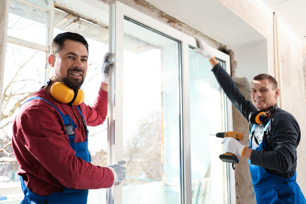 Workers using electric screwdriver for window installation indoors - Φωτογραφία, εικόνα