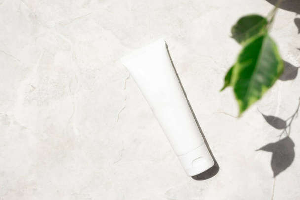 Hand or facial moisturizer cream in white plastic tube on marble background with copy space. Concept of natural cosmetic - Valokuva, kuva