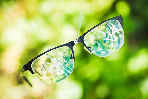 stłuczone okulary na zielonym tle natury. koncepcja awarii na ulicy - Zdjęcie, obraz
