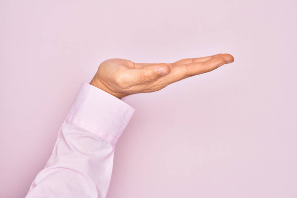 Mão do jovem caucasiano mostrando os dedos sobre fundo rosa isolado com palma plana apresentando produto, oferta e dando gesto, espaço em branco cópia - Foto, Imagem