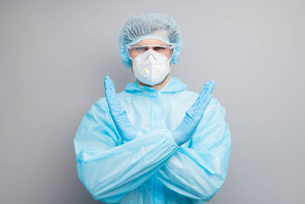 Photo of expert doc virologist guy crossing palms stop hold patients out of danger infected zone wear gloves mask hazmat blue uniform surgical cap goggles isolated grey color background - Foto, imagen