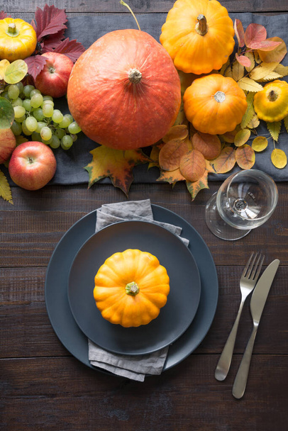 Fall table place setting with orange dry leaves and pumpkins. Vertical format. Centerpieces Thanksgiving Day. View from above. - Foto, Bild