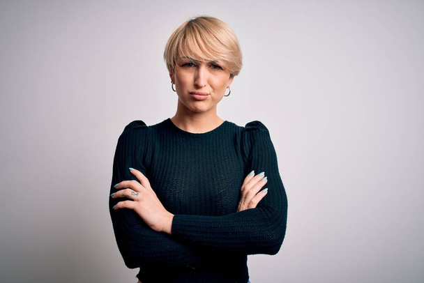 Young beautiful blonde woman with modern short hair hairstyle standing over isolated background skeptic and nervous, disapproving expression on face with crossed arms. Negative person. - Fotografie, Obrázek