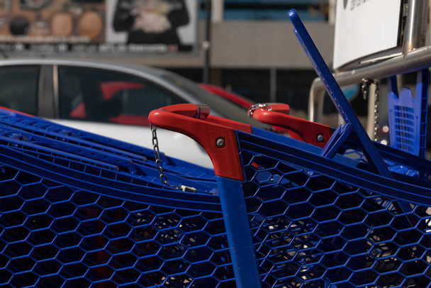 Wózki sklepowe w kolorze niebieskim, wykonane z tworzywa sztucznego, przechowywane na zewnątrz parkingu dużego centrum handlowego, w dzielnicy Ciudad de la Imagen, Madryt, Hiszpania. - Zdjęcie, obraz