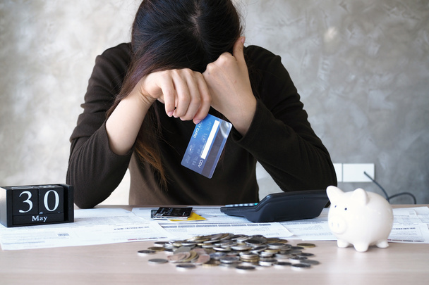 Une jeune femme avec une dette de carte de crédit et de nombreux billets placés sur la table. - Photo, image
