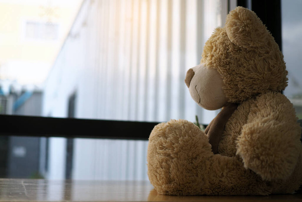 Child concept of sorrow. Teddy bear sitting leaning against the wall of the house alone, look sad and disappointed. - Photo, Image