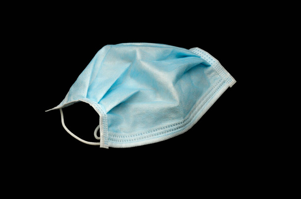 Izolacja niebieskiej maski ochronnej koronawirusa na czarnym tle. - Zdjęcie, obraz