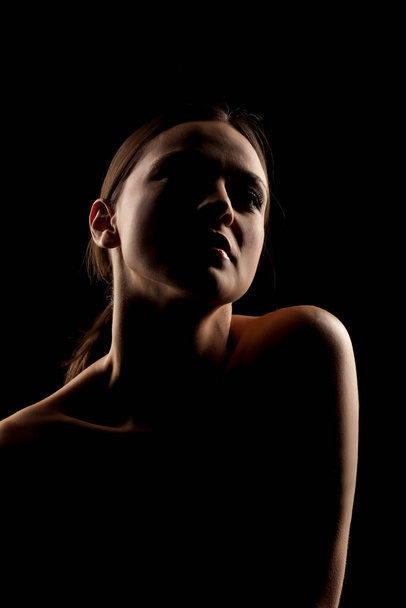 silhouette portrait of a woman with naked shoulders on a black background - Valokuva, kuva