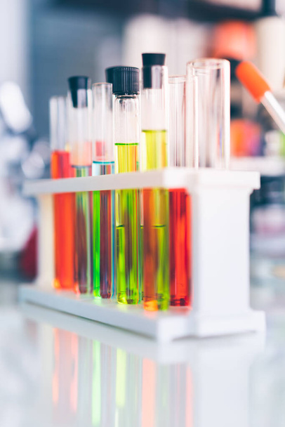 Testbuizen met kleurrijke chemicaliën op witte tafel. - Foto, afbeelding