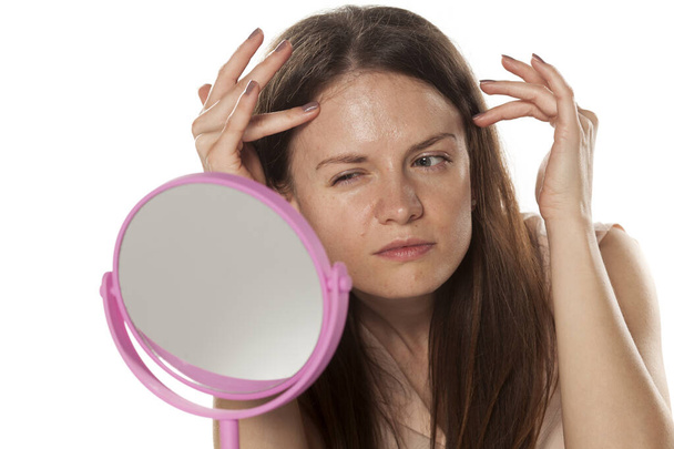 young woman without make-up looks at mirror her wrinkles - Photo, Image