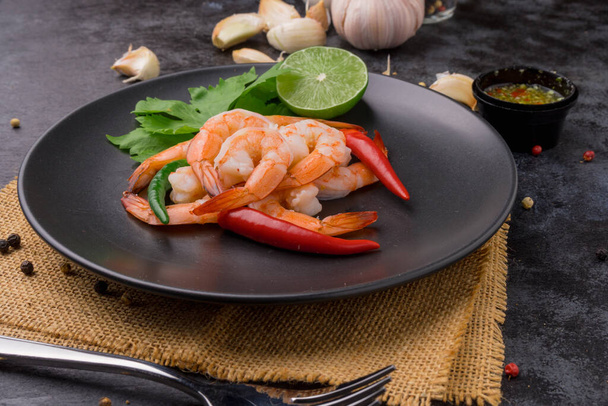 Camarões em prato preto com molho de frutos do mar na mesa preta
. - Foto, Imagem