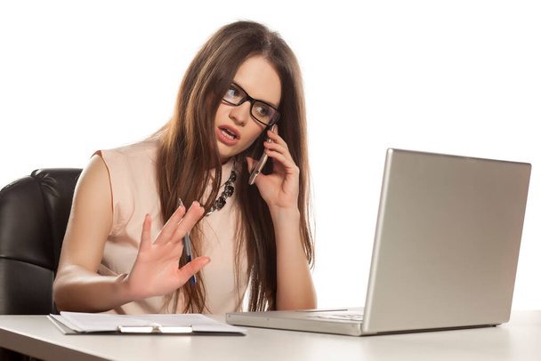 молода бізнес-леді працює на ноутбуці, розмовляє по телефону і пише
 - Фото, зображення