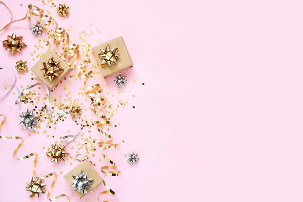 Beautiful composition with golden ribbons and gifts on a pink background. Box with presents. View from above. - Photo, image