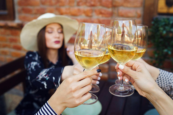 Close-up em copos de vinho branco nas mãos de mulheres comemorando a torrada
 - Foto, Imagem