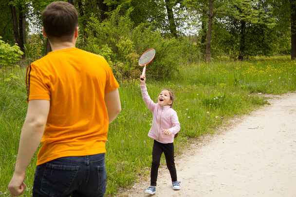 A five-year-old girl and a young boy play badminton in the park. It's brother and sister. - Zdjęcie, obraz