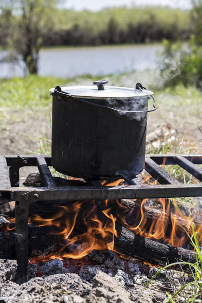 Cooking a meal on a campfire. Cooking in a pot over campfire. Camp in the forest. Field kitchen. - Foto, afbeelding