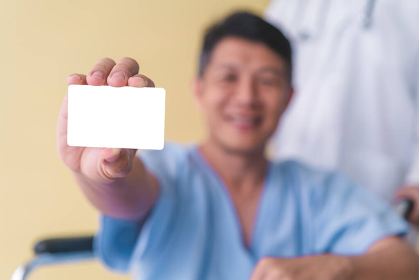 Asian senior patient wheelchair showing white card. - Foto, Bild