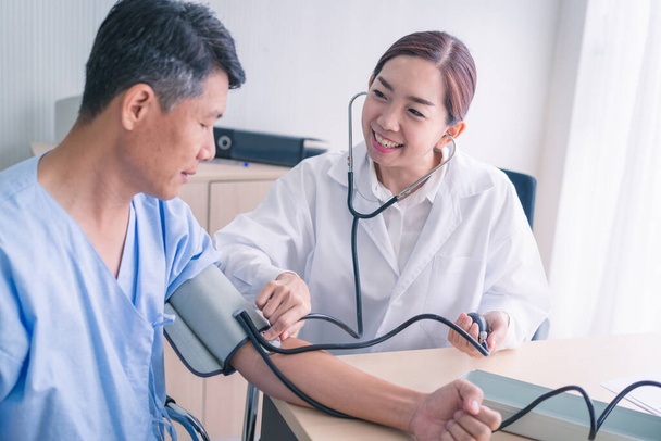 Médico mujer midiendo la presión arterial del paciente masculino
. - Foto, Imagen