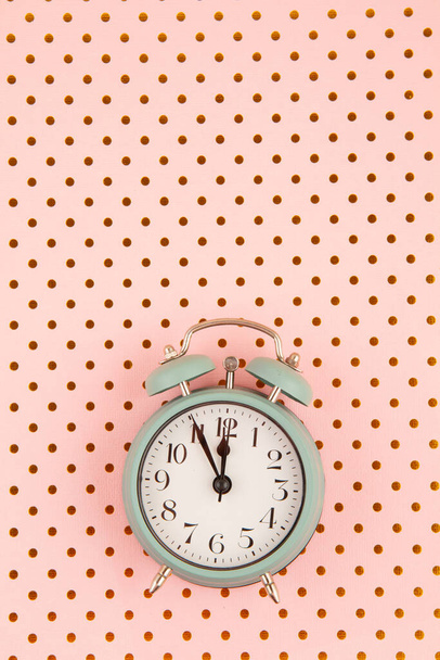 Colocación plana con reloj despertador vintage sobre el fondo rosa pastel con lunares dorados
 - Foto, Imagen