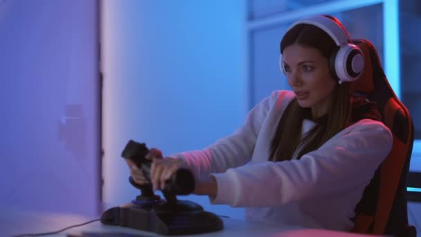 The beautiful gamer girl with headphones plays video games in the blue light room - Footage, Video