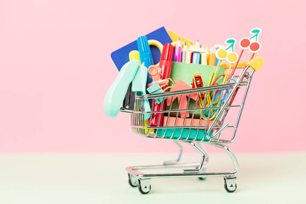 Shopping trolley full of school supplies. Preparation to school, shopping, sale, deals, discounts, promotion concept - Photo, Image
