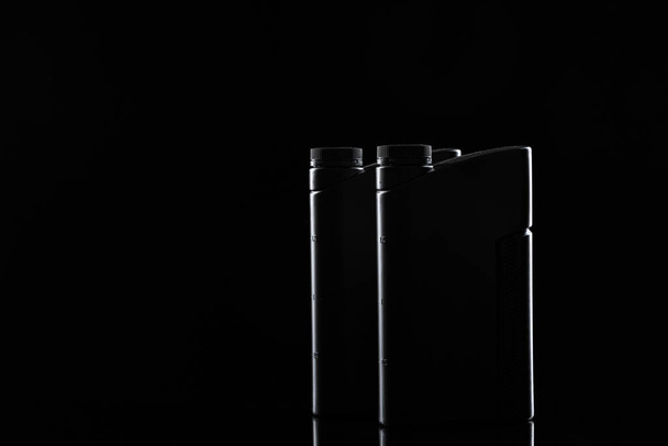 Engine oil bottle on black background, close up. - Zdjęcie, obraz