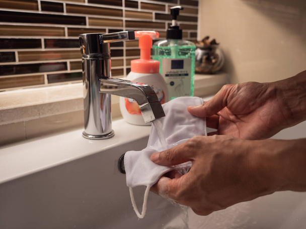 Lähikuva mies kädet pesemällä kasvonsa naamio nestemäistä keittoa ja vettä. Valittu painopiste. - Valokuva, kuva