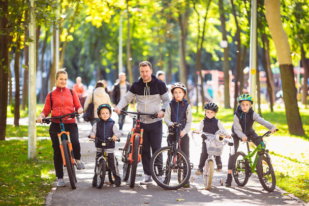 Thema familie actieve sport outdoor recreatie. Een groep mensen is een grote familie van 6 personen die poseren op mountainbikes in een stadspark op een weg op een zonnige dag in de herfst. - Foto, afbeelding