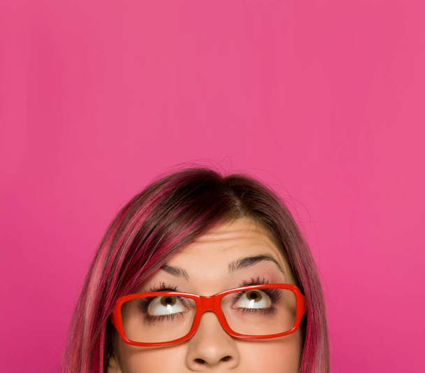 Mezzo ritratto di una giovane donna preoccupata con capelli rosa e occhiali su sfondo rosa
 - Foto, immagini