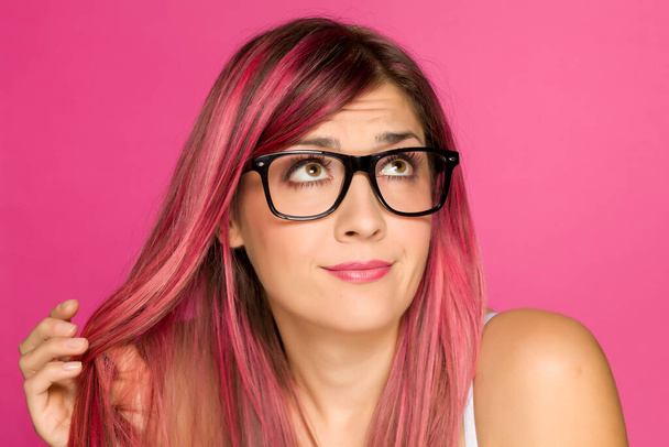joven mujer preocupada con el pelo rosa sobre un fondo rosa
 - Foto, Imagen