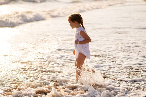 little girl walks and fun on sea shore with big waves and strong winds. - Foto, Imagen