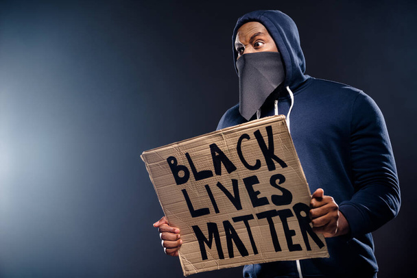 Profile side photo of shocked afro american guy hold banner impressed police community injustice racism issues wear sweater jumper isolated over black color background - Valokuva, kuva
