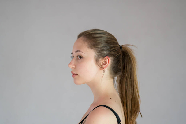 Kameraya bakan uzun doğal sarı saçlı ve pürüzsüz tenli güzel bir genç kızın portresi. Stüdyo çekimi - Fotoğraf, Görsel