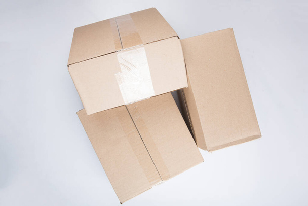 plan rapproché isolé de trois boîtes en carton brun vides rectangulaires empilées et fermées sur fond blanc - Photo, image