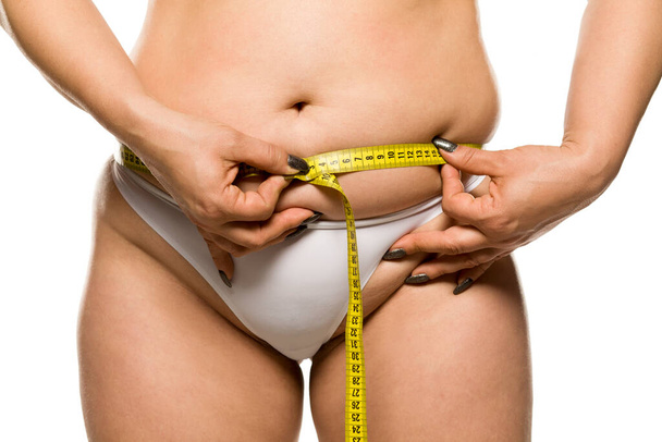 una mujer gorda midiendo su vientre sobre fondo blanco
 - Foto, Imagen