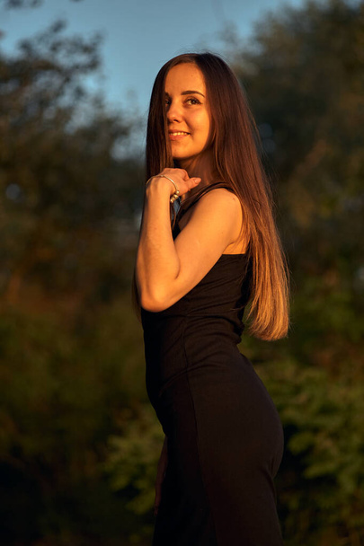 Beautiful girl on the nature near the green shore. Enjoys the setting sun. The concept of outdoor recreation, a walk in the park. Relaxation from the bustle of the city. - Fotó, kép