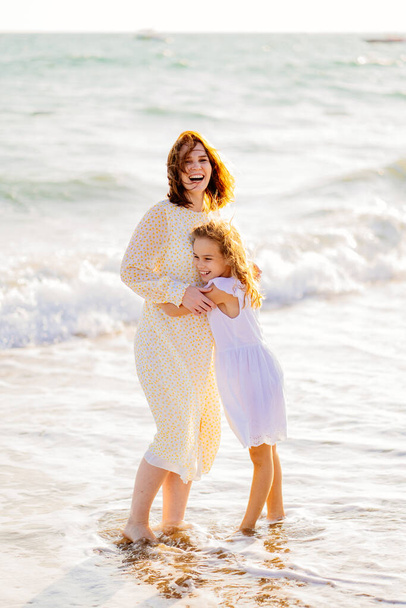 mom and kid walking on sea beach with big waves in windy weather. happy family - Foto, immagini