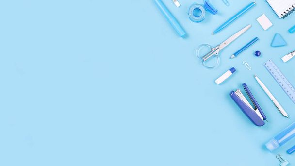 Assorted office and school white and blue stationery on pastel background as border. Flat lay knolling with copy space for back to school or education and craft concept. Blue monochrome banner - 写真・画像
