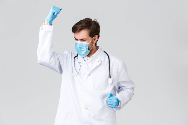 Лікарня, медичні працівники, концепція лікування ковадла-19. Доктор відчуває себе чемпіоном, носить медичну маску і рукавички, кулак насос радість, радіє перемозі, перемагає хворобу, лікує пацієнта
 - Фото, зображення