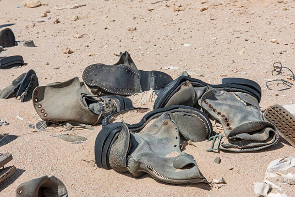 Fechar as velhas botas militares em decomposição abandonadas na remota paisagem do deserto africano
 - Foto, Imagem