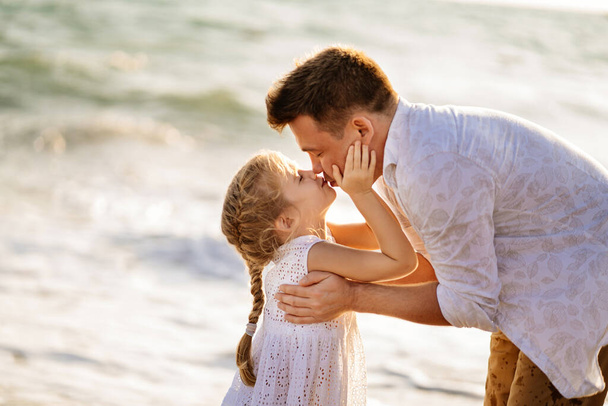 kiss. dad with daughter walking along sea-shore in windy weather. fun family. - Fotoğraf, Görsel
