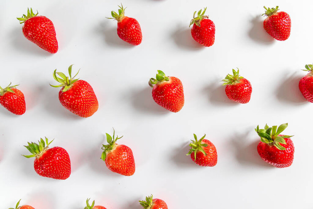 Bio köstliche Erdbeeren nahtlose Muster auf grauem Hintergrund, von oben gesehen, flache Lage. Sommerliche Komposition, minimaler Stil - Foto, Bild