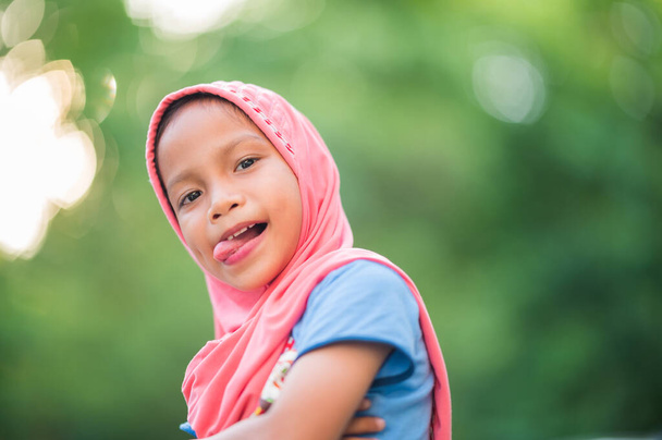 Porträt eines jungen muslimischen Mädchens, mit rotem Tuch bedeckt, lächelnd, glücklich und kopierend in die Kamera - Foto, Bild